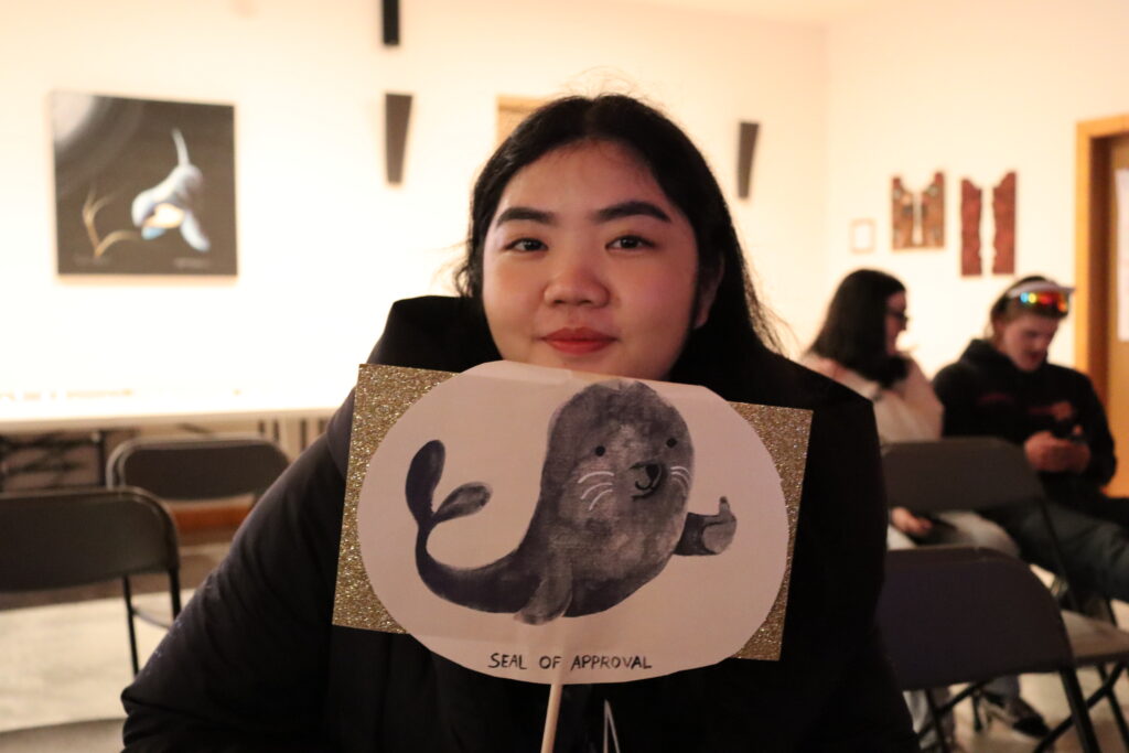 Young woman holding Sea Otter arts sign at wildlife conservation event.