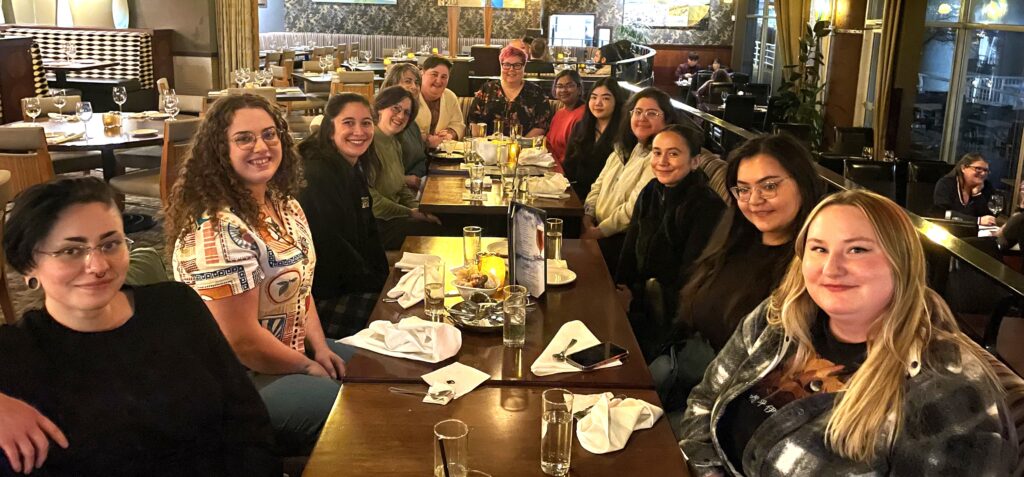 Group of staff, smiling, sitting around a table at a restaurant.